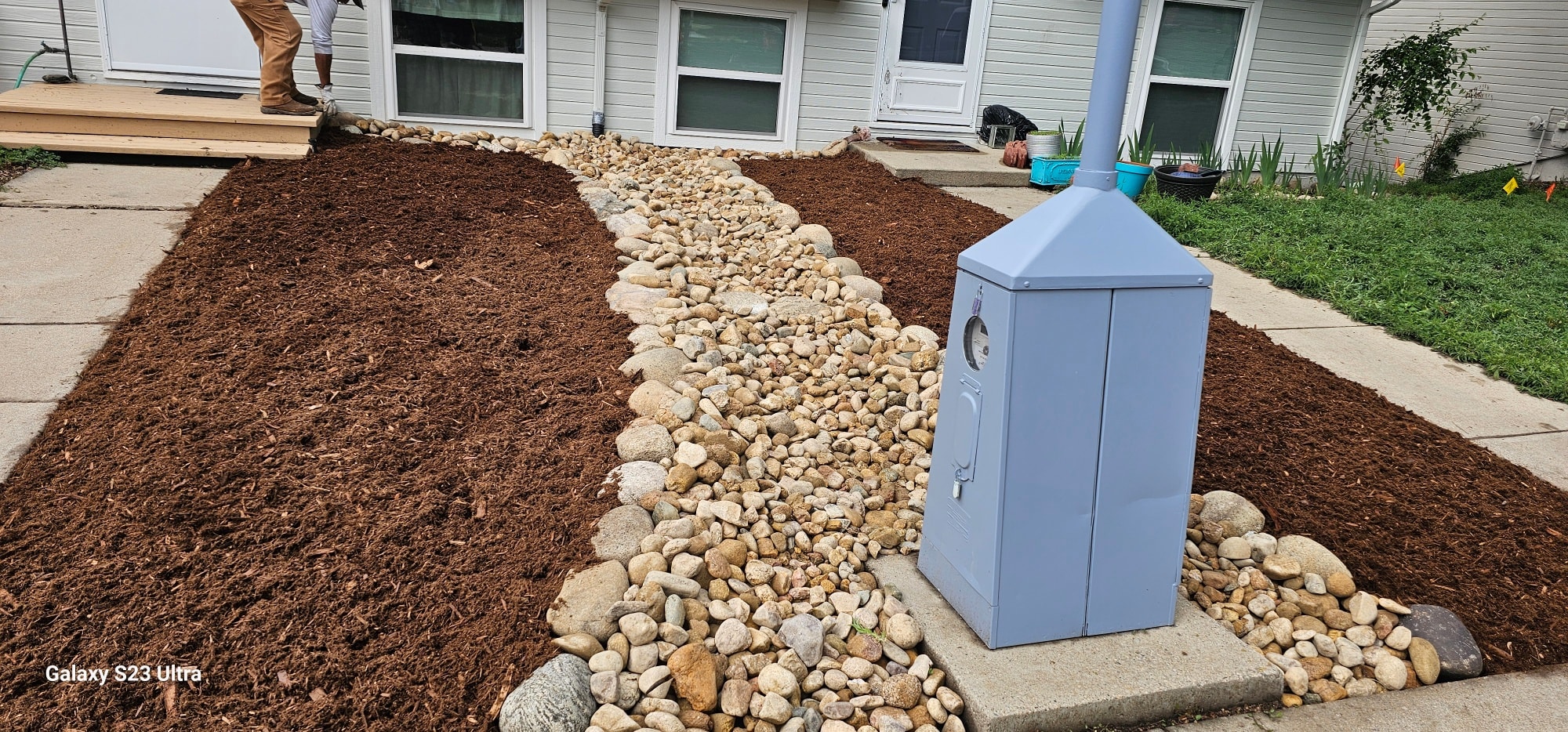 Custom natural stone slab stairs installed on a sloped backyard with grey gravel mulch and young shrubs.