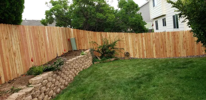 A freshly installed green sod lawn in a backyard surrounded by a new wood perimeter fence and gravel walkway.